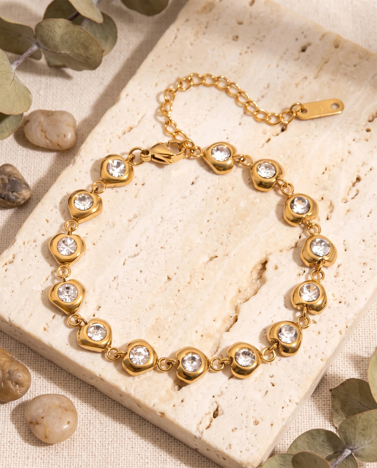 Goldenes Cara Zirkonia Armband aus Edelstahl auf hellem Stoff