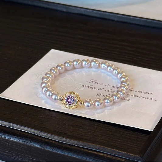 Lia's Lavendel-Blüte Armband aus zartvioletten Kunstperlen mit einem blumenförmigen goldenen Anhänger und violettem Zirkonia