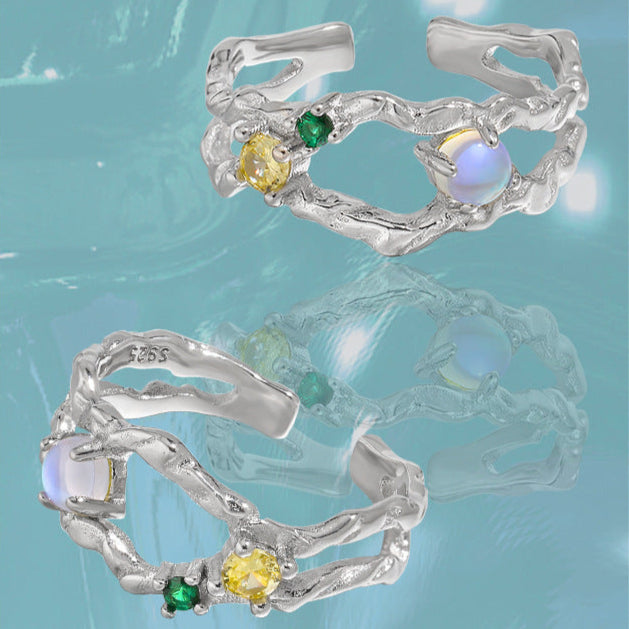 Offener Damenring aus 925er Silber mit leuchtendem Mondstein und bunten Zirkonia, präsentiert auf AURAGLEAM-Karte – elegantes, kunstvolles Design
