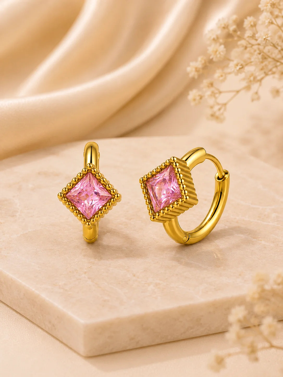 Rosa Quadrat-Zirkonia Creolen aus 18K vergoldetem Titanstahl in einer hellen Keramikschale