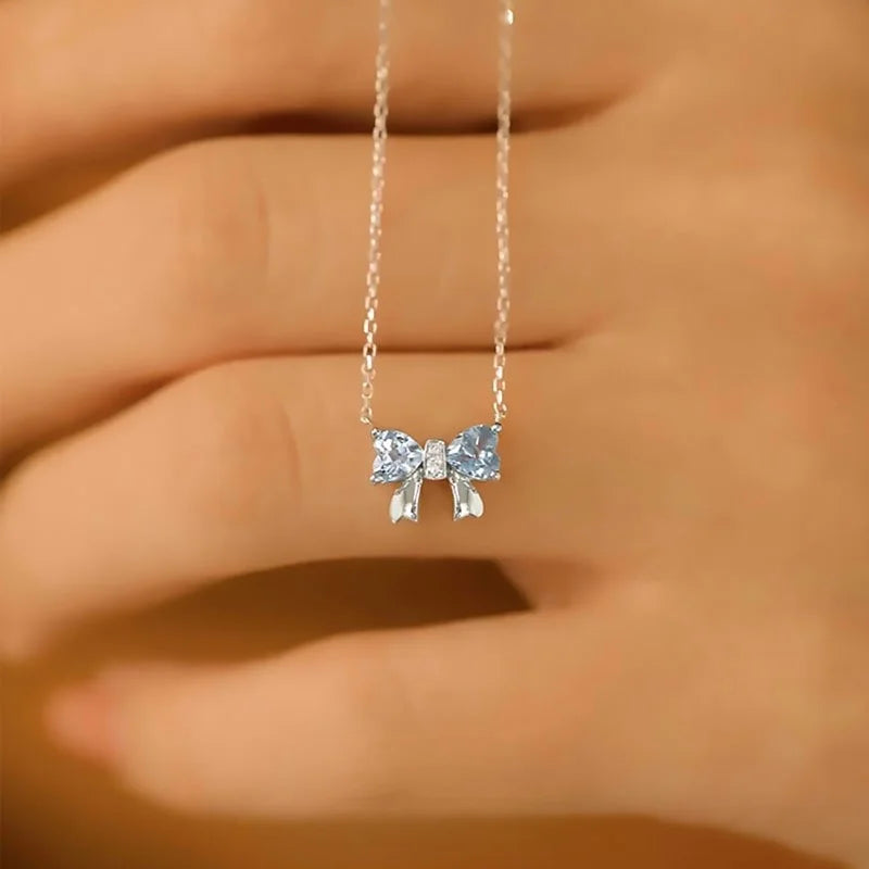 Silberne Halskette mit Anhänger in Schleifenform aus zwei blauen herzförmigen Steinen