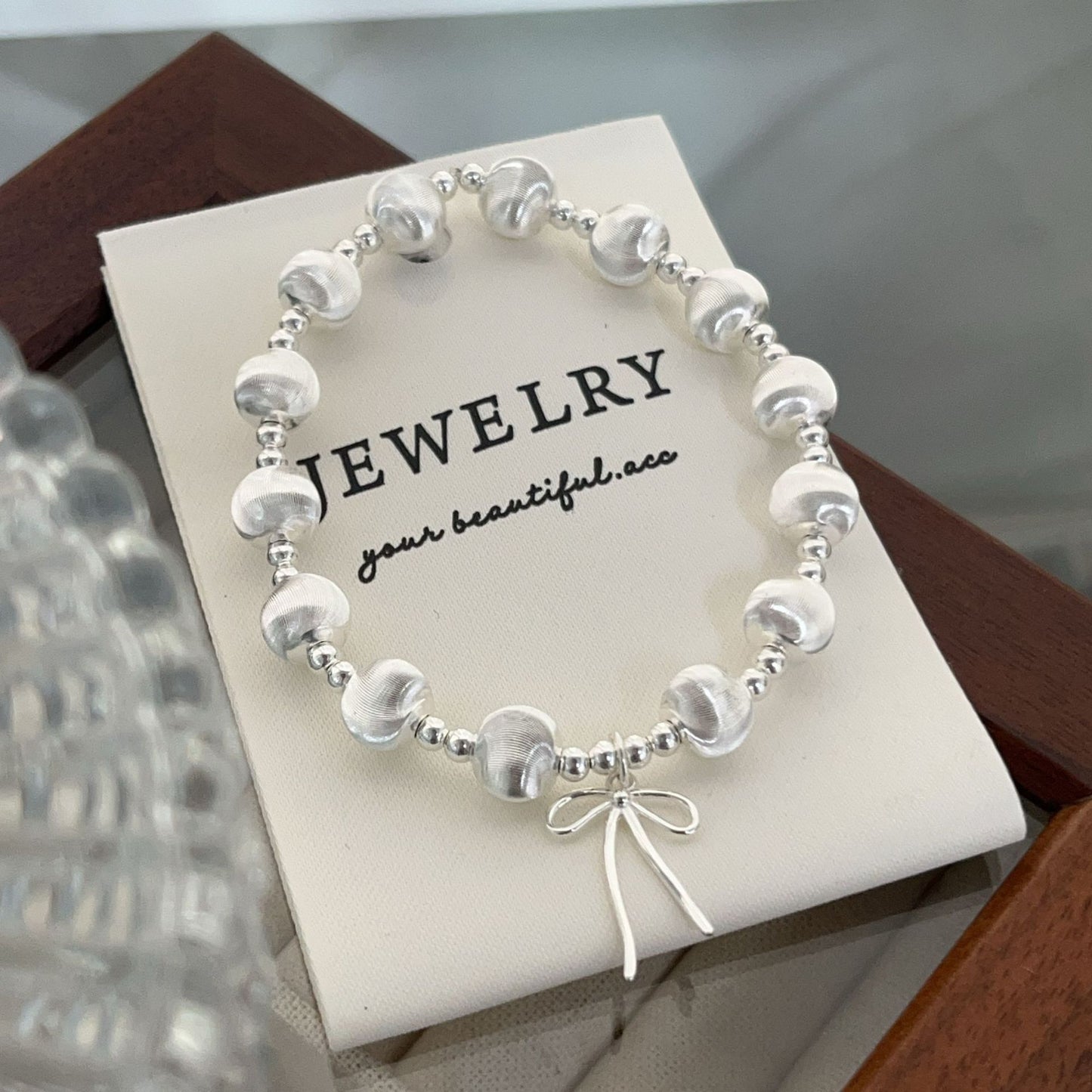 Handgefertigtes Armband aus 925er Silber mit schimmernden Katzenaugenperlen und Schleifenanhänger – elegant und verspielt