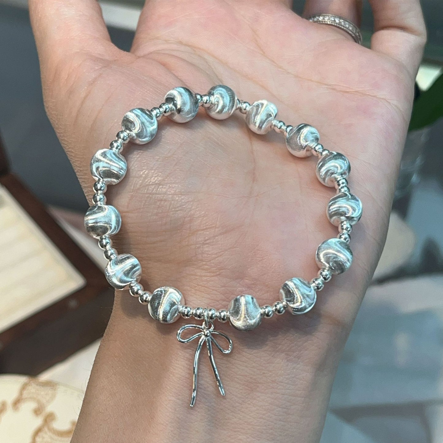 Handgefertigtes Armband aus 925er Silber mit schimmernden Katzenaugenperlen und Schleifenanhänger – elegant und verspielt