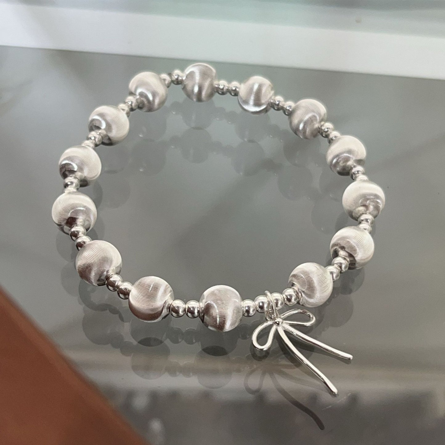 Handgefertigtes Armband aus 925er Silber mit schimmernden Katzenaugenperlen und Schleifenanhänger – elegant und verspielt