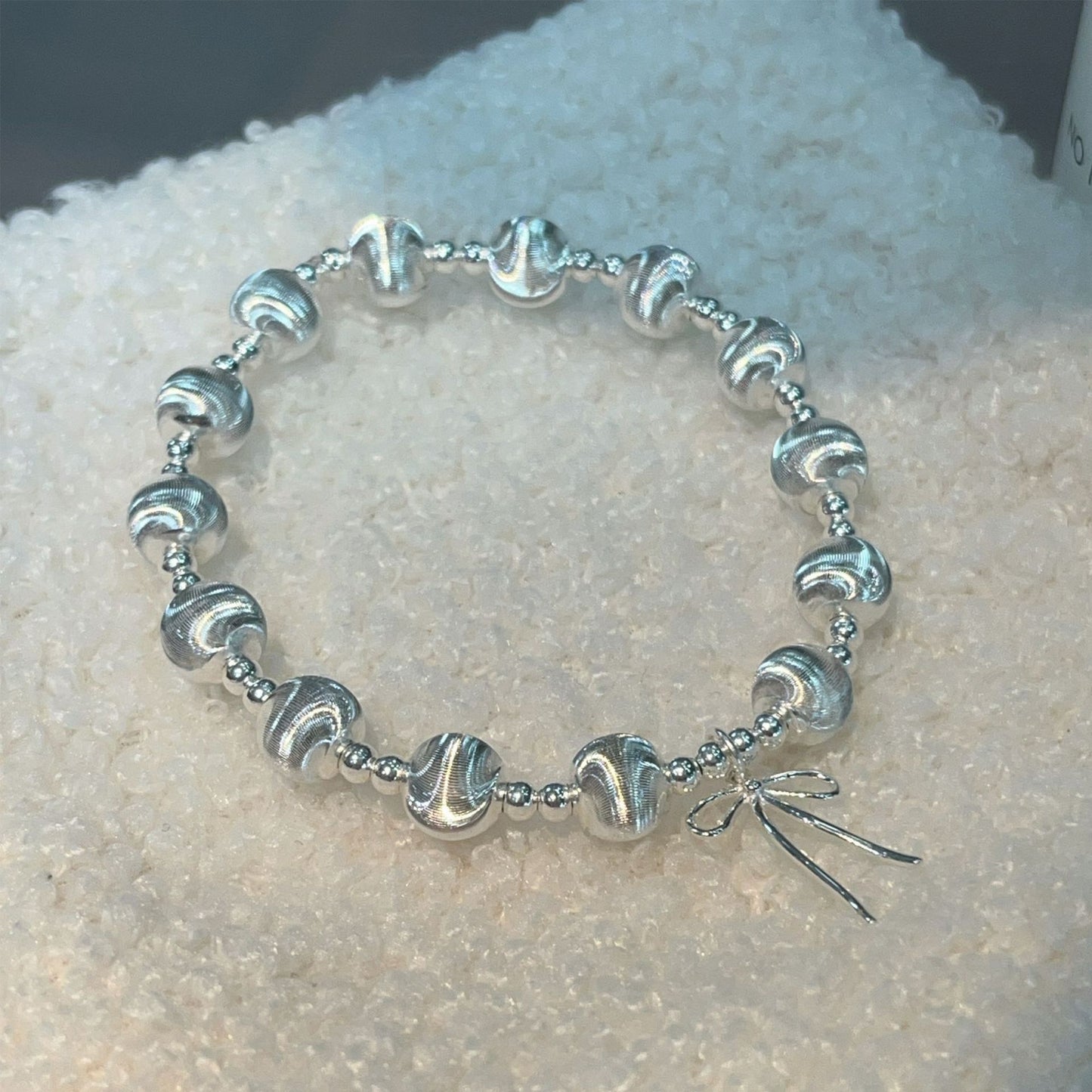 Handgefertigtes Armband aus 925er Silber mit schimmernden Katzenaugenperlen und Schleifenanhänger – elegant und verspielt
