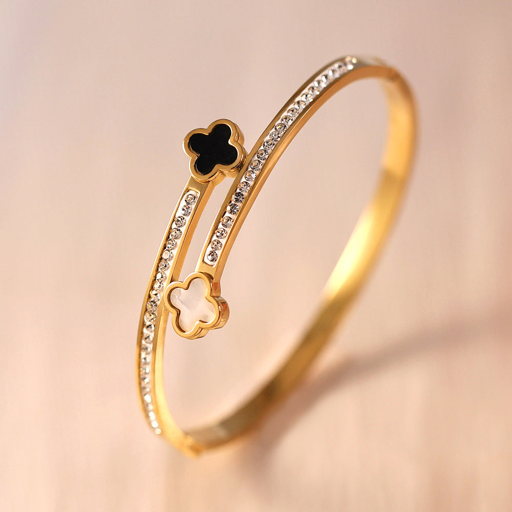 Vergoldeter Armreif mit schwarzen und weißen Kleeblatt-Elementen und Zirkonia