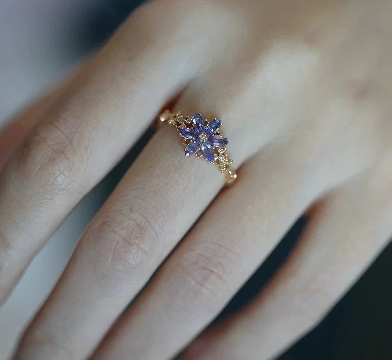 Goldener Ring mit lila Zirkonia Schneeflocke an einer Frauenhand