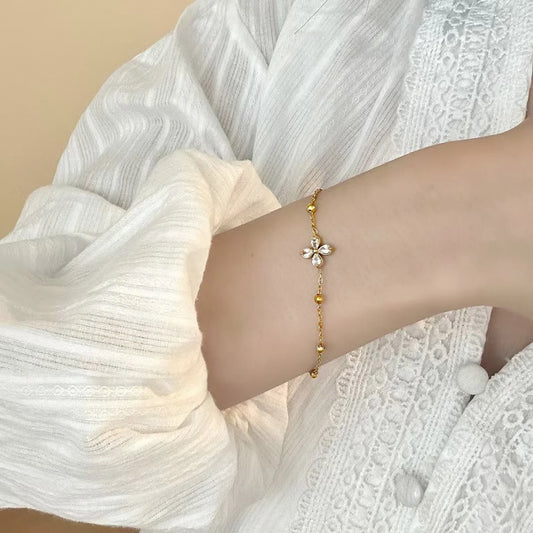 Zartes Blüten-Glanz Armband aus vergoldetem Titanstahl mit Zirkonia-Blüte und Goldperlen auf goldenem Satin