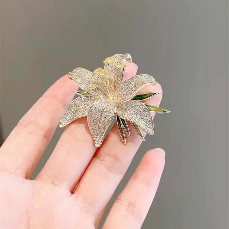Goldfarbene Lilien-Brosche mit grüner Emaille und funkelnden Zirkonia – eleganter Blütenschmuck mit Naturinspiration