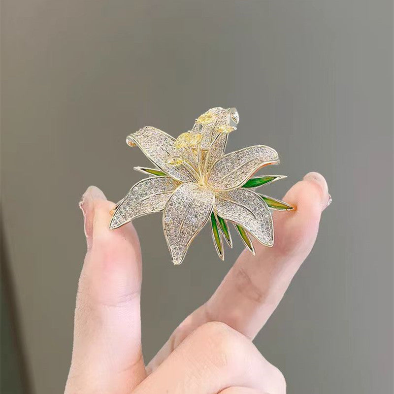 Goldfarbene Lilien-Brosche mit grüner Emaille und funkelnden Zirkonia – eleganter Blütenschmuck mit Naturinspiration