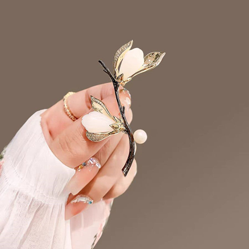 Elegante Magnolien-Brosche mit goldfarbenen Blütenblättern, Zirkoniabesatz und einer zarten Süßwasserperle – femininer Natur-Schmuck im asiatischen Stil