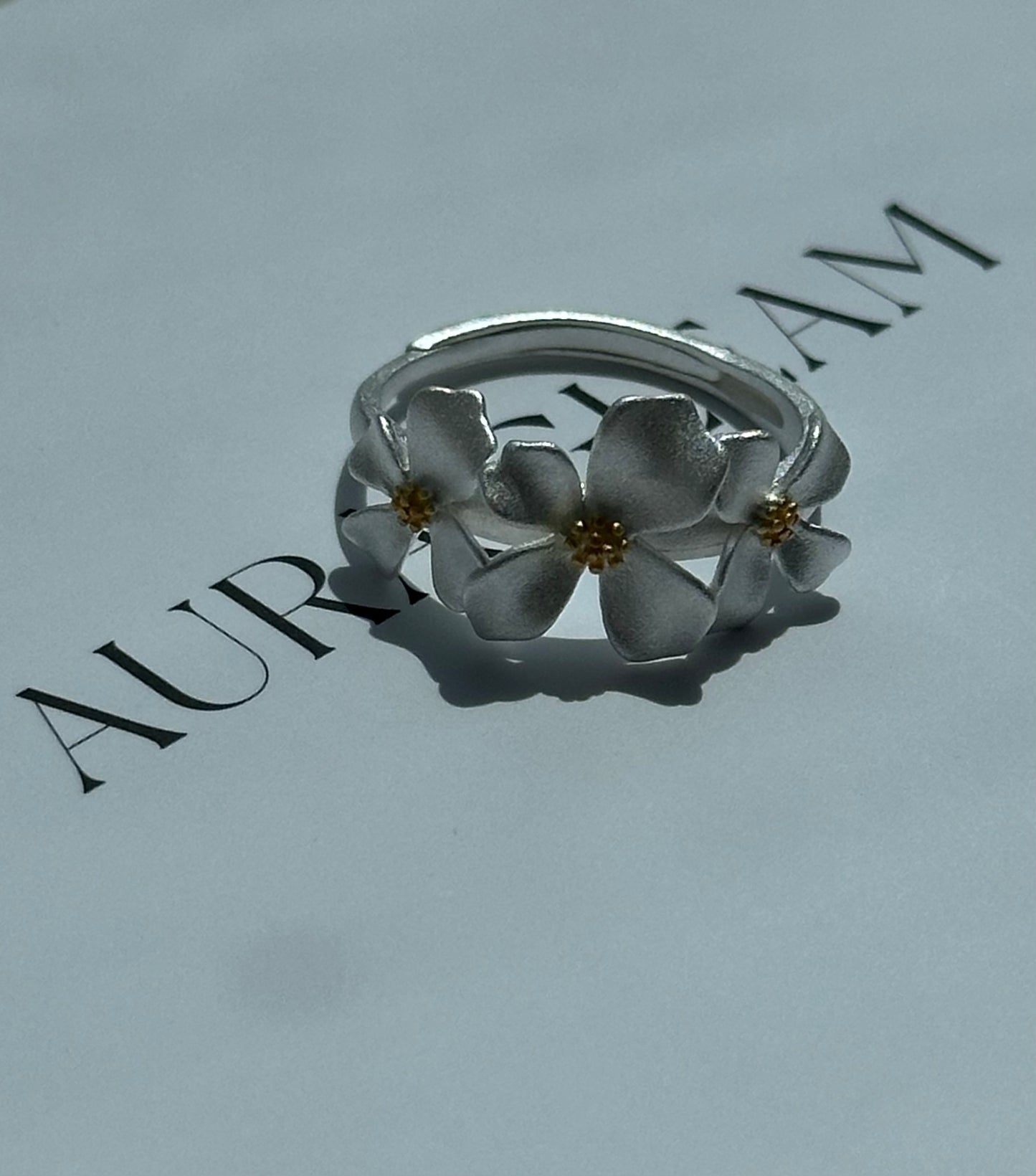 Verstellbarer Ring aus S999 Feinsilber mit drei zarten Gardenienblüten – florales Design mit goldfarbenem Blütenstempel für einen eleganten Naturlook