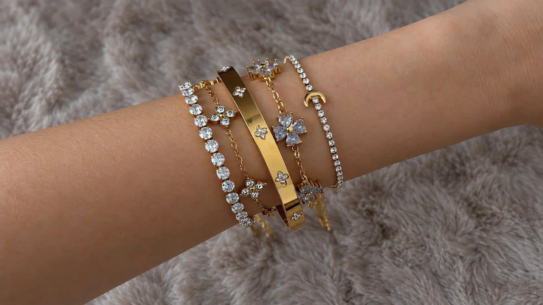 Goldene Armbänder und Armreif mit Zirkonia, Blumenmotiven und Mond-Detail übereinander am Handgelenk getragen