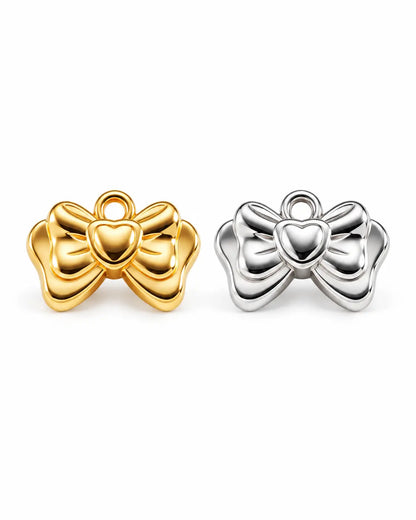 Amelie Schleifen Charms in Gold und Silber aus Edelstahl mit plastischem Schleifenmotiv und Herzdetail auf Weiß