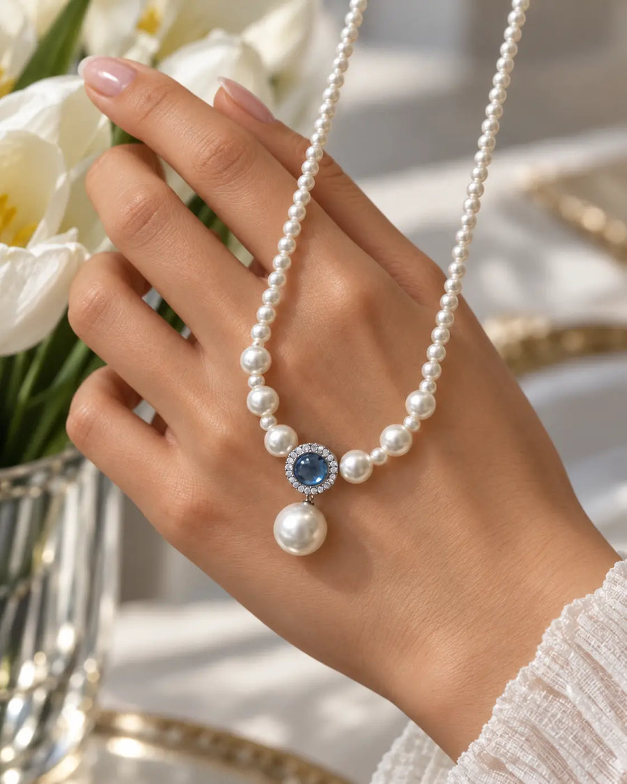 Aqua Grace Perlenkette über einer Hand neben weißen Tulpen