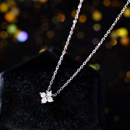 Feine Silberkette mit funkelndem Blütenanhänger aus vier Zirkonia-Steinen auf schwarzem Hintergrund.