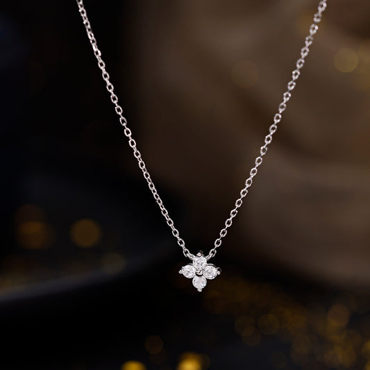 Feine Silberkette mit funkelndem Blütenanhänger aus vier Zirkonia-Steinen auf schwarzem Hintergrund.