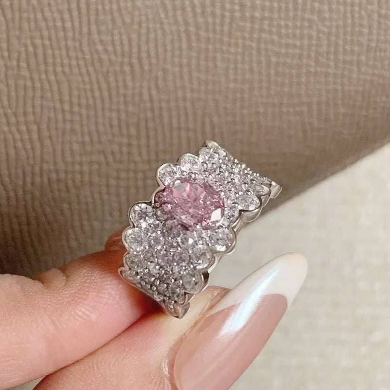 Breiter silberner Ring mit vielen kleinen Steinen und großem rosa Zirkonia in der Mitte