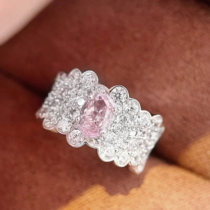 Breiter silberner Ring mit vielen kleinen Steinen und großem rosa Zirkonia in der Mitte