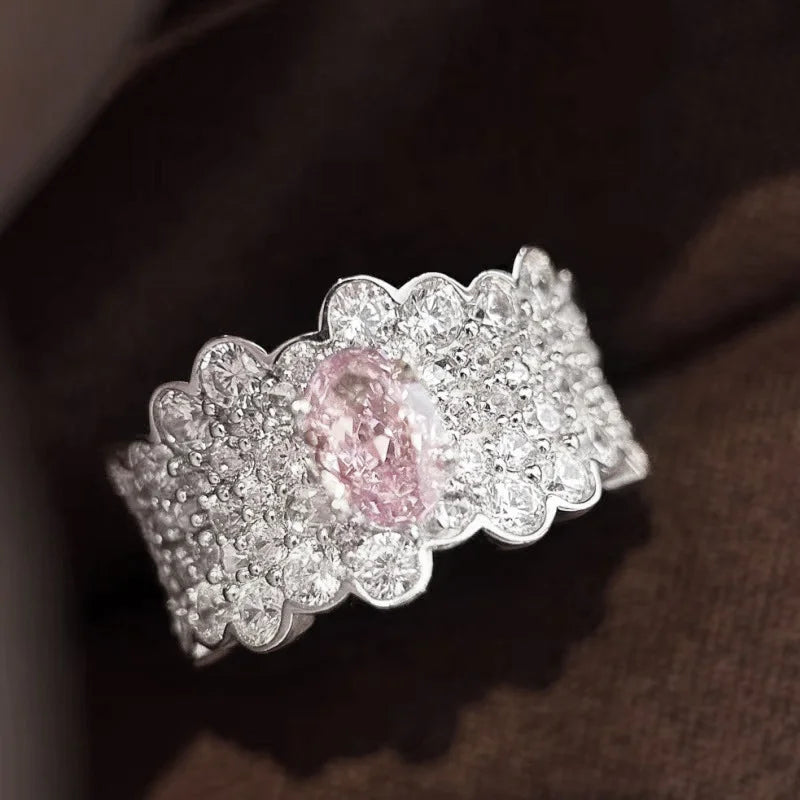 Breiter silberner Ring mit vielen kleinen Steinen und großem rosa Zirkonia in der Mitte