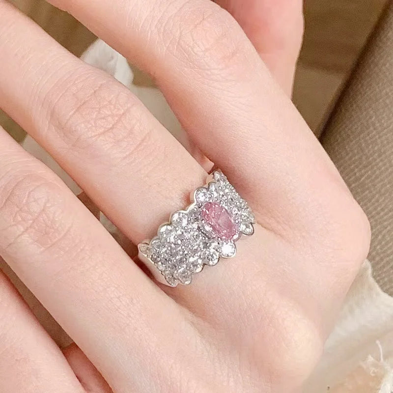 Breiter silberner Ring mit vielen kleinen Steinen und großem rosa Zirkonia in der Mitte