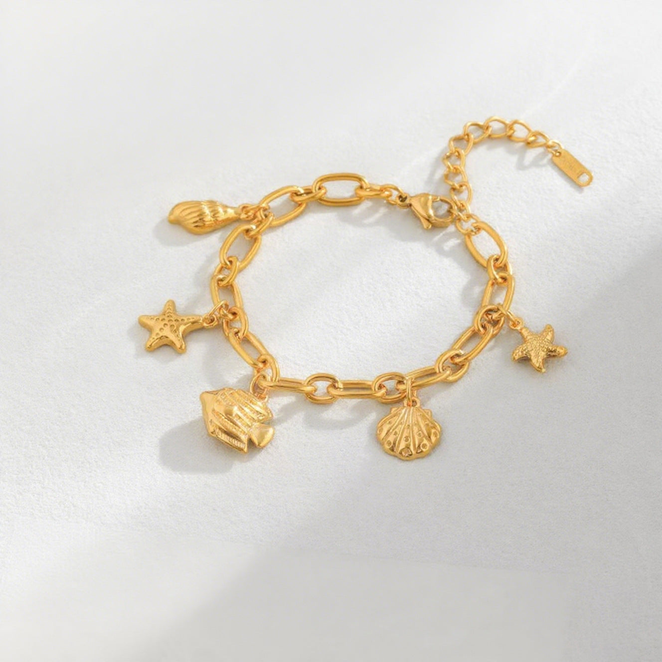 Vergoldetes Gliederarmband mit maritimen Anhängern wie Seestern, Fisch und Muschel in sommerlichem Design.