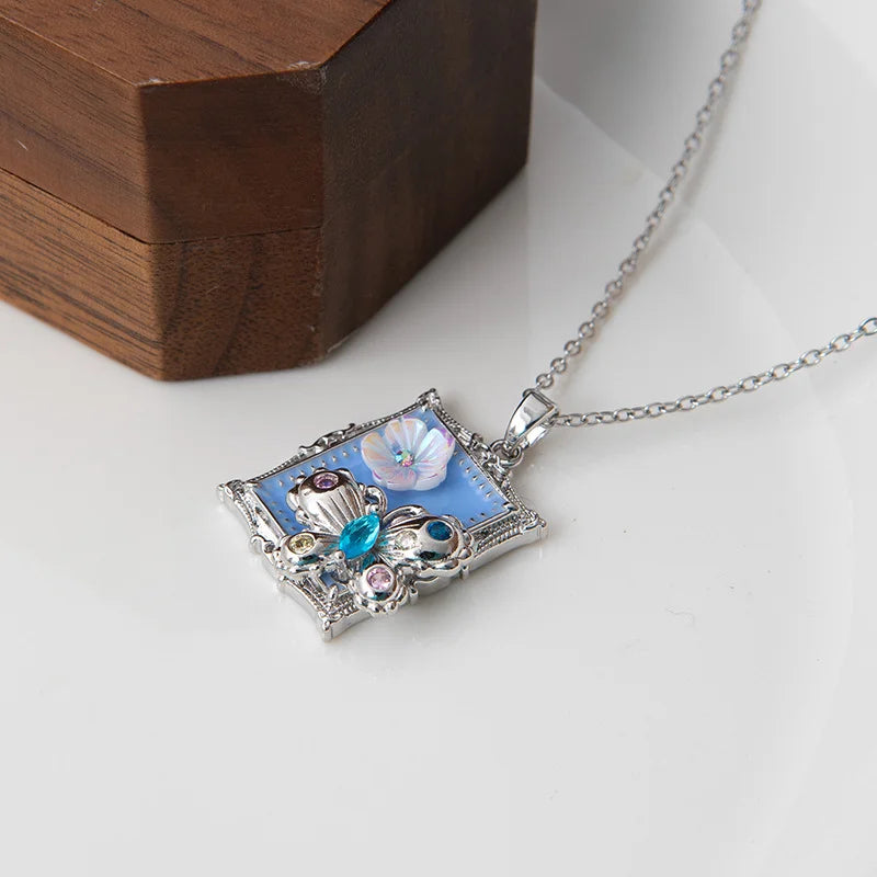 Silberne Halskette "Clara" aus Edelstahl mit rechteckigem Bilderrahmen-Anhänger, blauer Emaille und buntem Kristall-Schmetterling