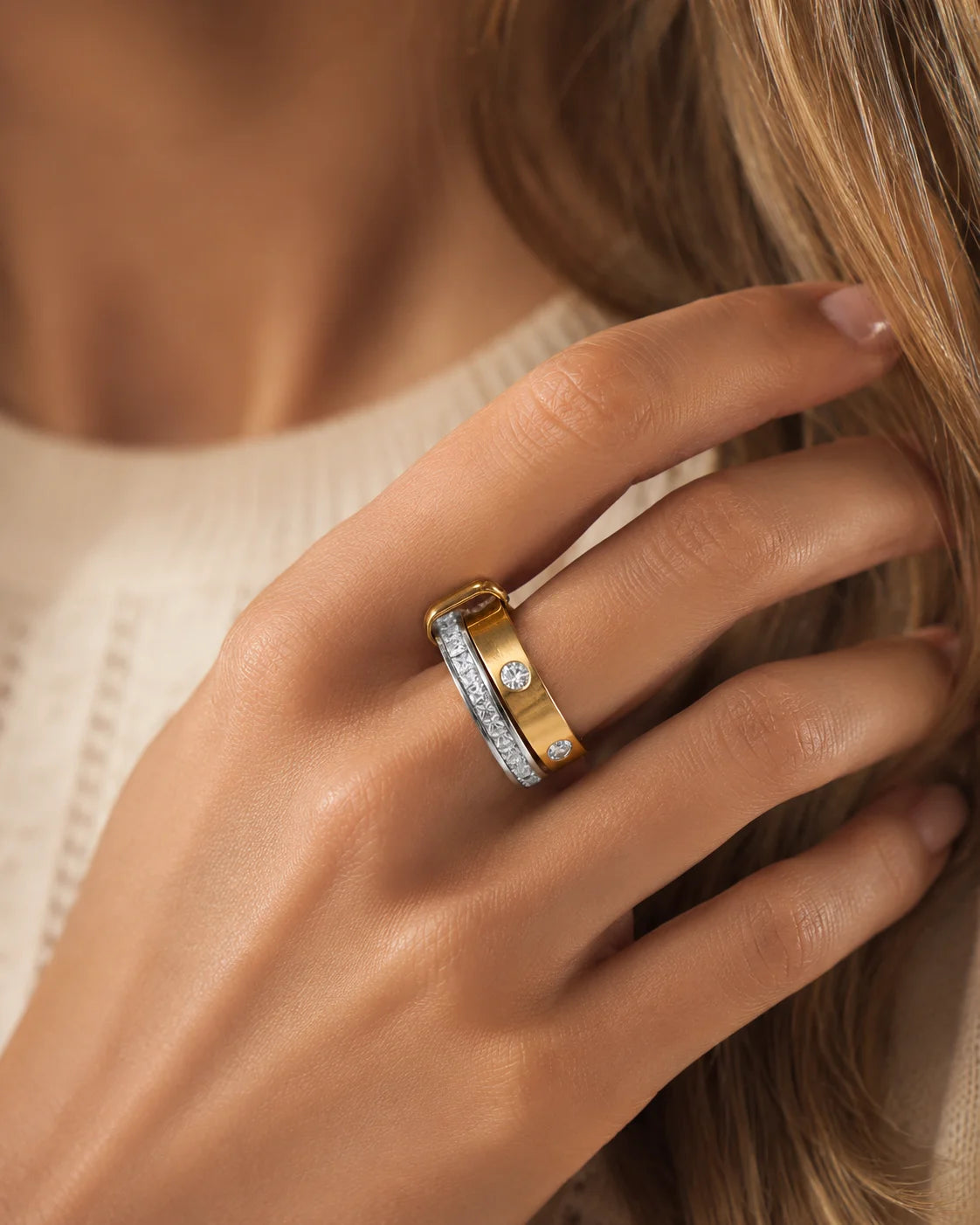 Geschlossener Bicolor-Doppelring aus Titanstahl, bestehend aus zwei ineinander verschlungenen Ringen – einer silberfarben mit durchgehenden Steinen, einer goldfarben mit einzeln gefassten Kristallen.