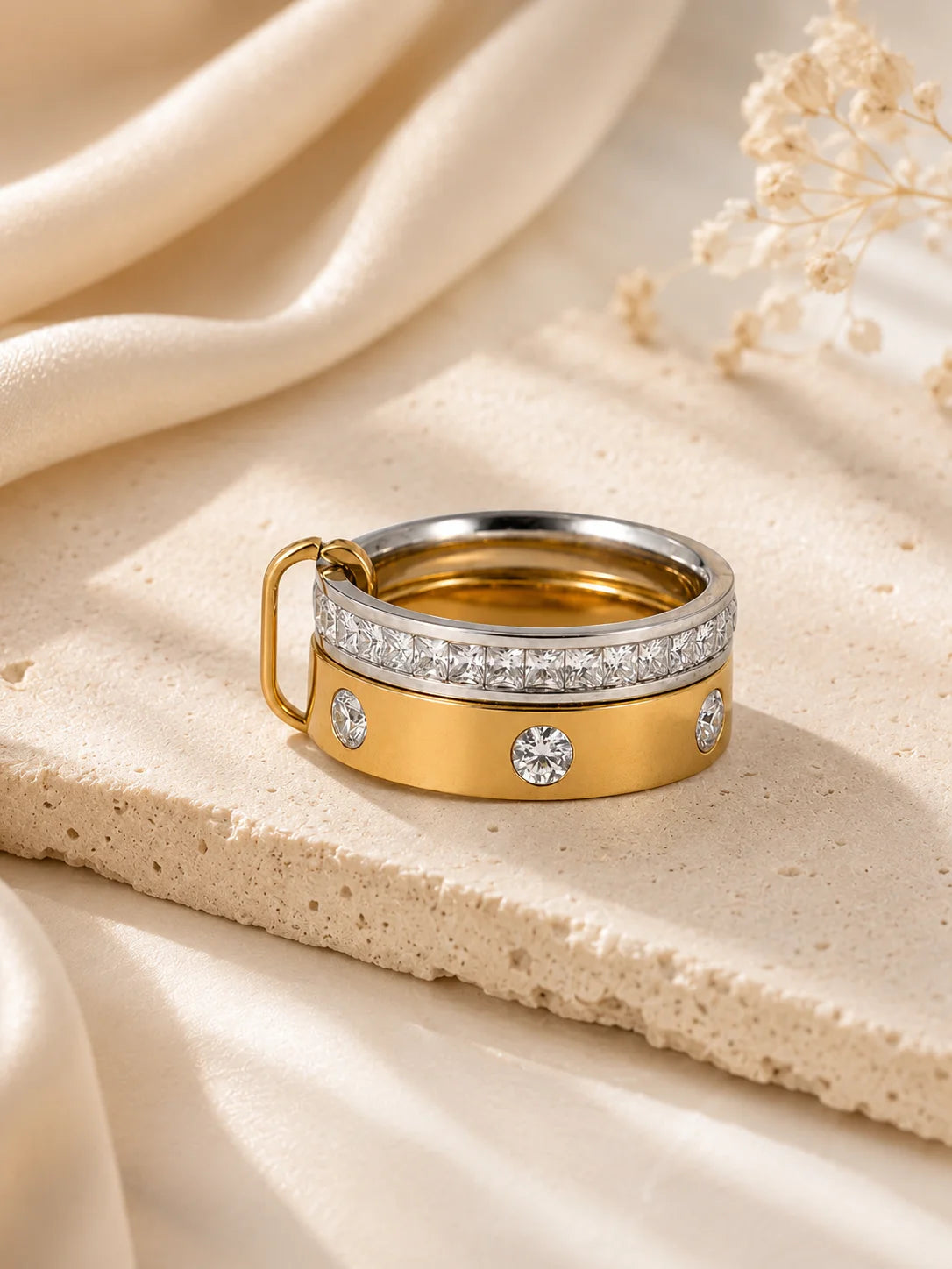 Geschlossener Bicolor-Doppelring aus Titanstahl, bestehend aus zwei ineinander verschlungenen Ringen – einer silberfarben mit durchgehenden Steinen, einer goldfarben mit einzeln gefassten Kristallen.