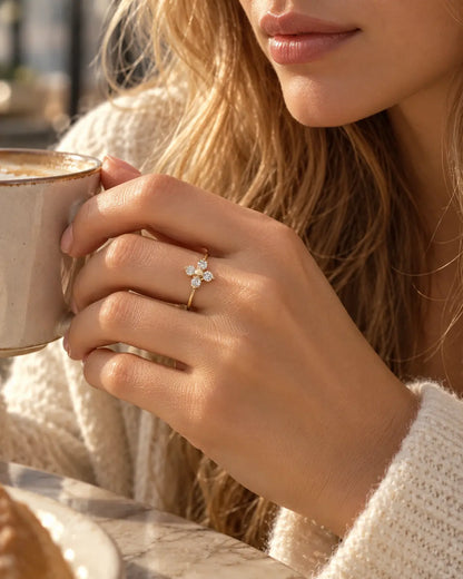 Frau im hellen Strickoberteil hält eine Tasse und trägt den goldenen Elina Zirkonia Blumenring