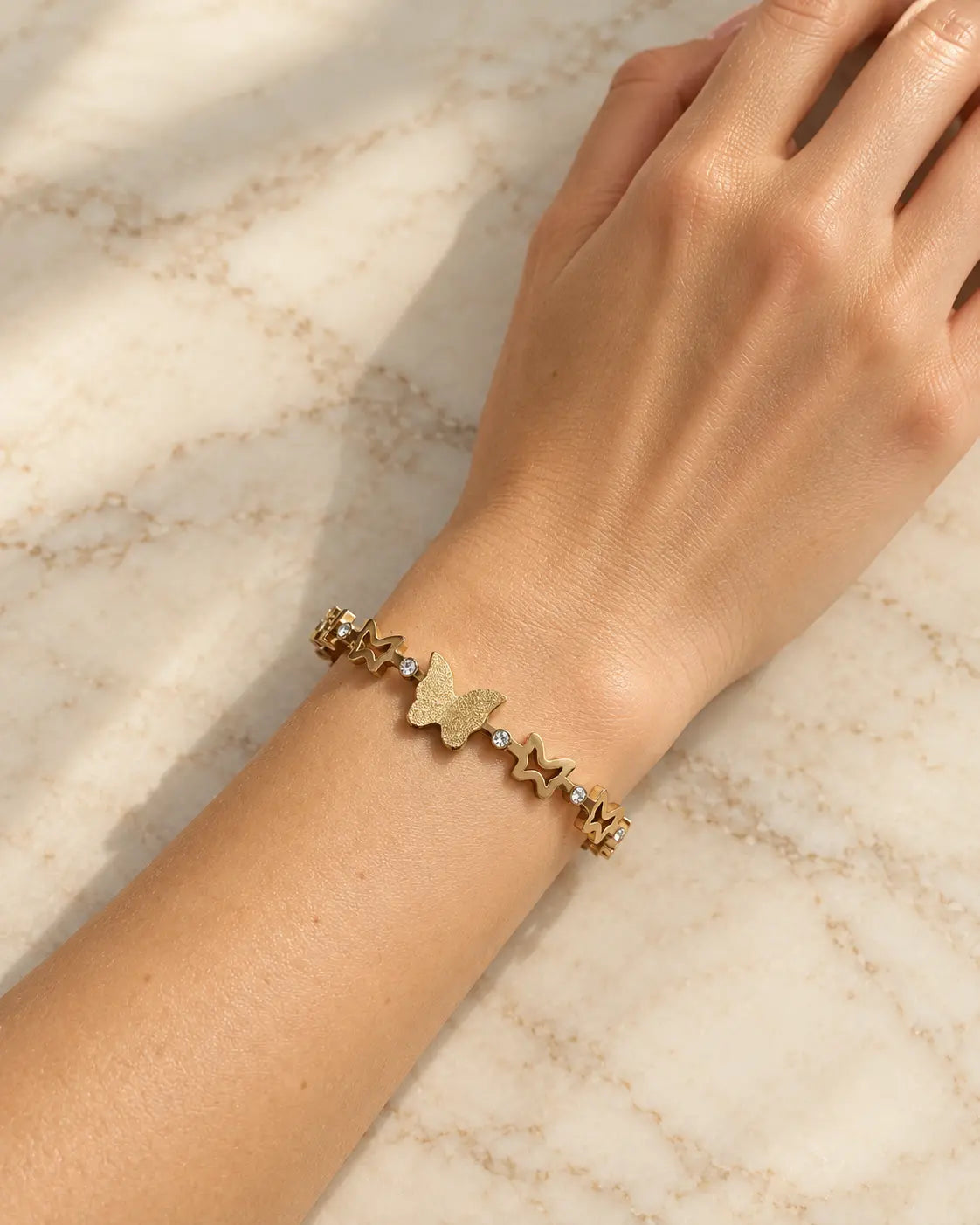 Glitzernder Schmetterling und Zirkonia am goldenen Armreif im Detail