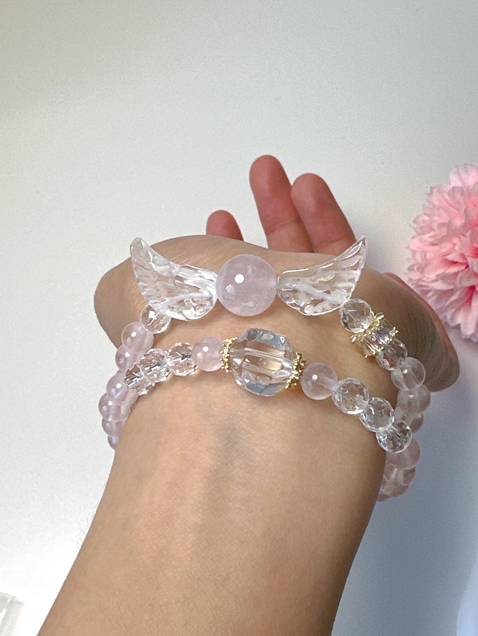 Doppellagiges Armband mit Rosenquarz, Bergkristall und Engelsflügel-Anhänger auf weißem Teller – zart und spirituell
