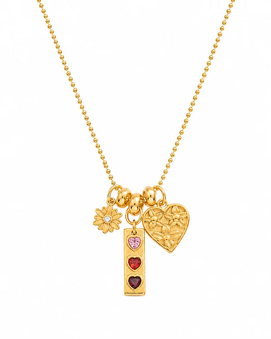 Goldene Kugelkette aus 18K vergoldetem Titanstahl mit drei verschiedenen Anhängern: einer Blume, einem länglichen Anhänger mit drei bunten Herzsteinen und einem geprägten Herz.
