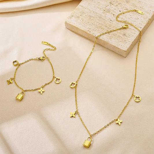 Goldenes Schmuckset aus Titanstahl bestehend aus Halskette und Armband mit Kleeblatt- und Schloss-Anhängern