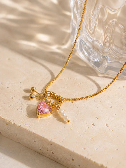 Charm-Halskette aus 18K vergoldetem Titanstahl mit gedrehtem Herz-Ring, rosa Kristallherz, goldenen Kirschen und Perlen-Anhängern