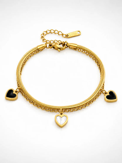 Zweilagiges Clara's Kontrast-Herzen Armband aus 18K vergoldetem Titanstahl mit drei schwarz-weißen Herzanhängern auf Marmorgrund