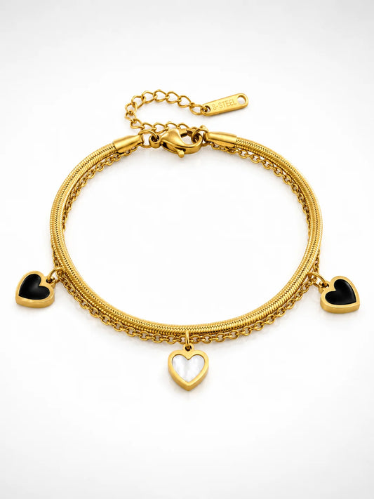 Zweilagiges Clara's Kontrast-Herzen Armband aus 18K vergoldetem Titanstahl mit drei schwarz-weißen Herzanhängern auf Marmorgrund
