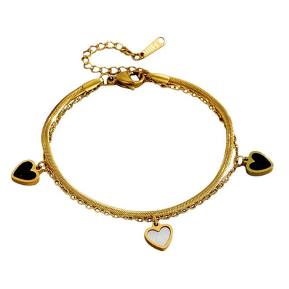 Zweilagiges Clara's Kontrast-Herzen Armband aus 18K vergoldetem Titanstahl mit drei schwarz-weißen Herzanhängern auf Marmorgrund