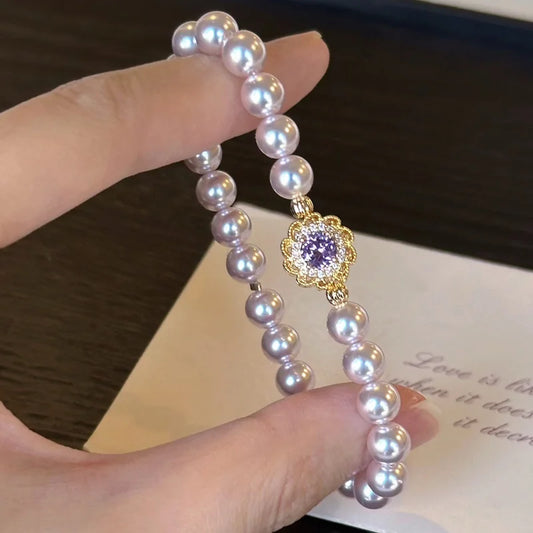 Lia's Lavendel-Blüte Armband aus zartvioletten Kunstperlen mit einem blumenförmigen goldenen Anhänger und violettem Zirkonia