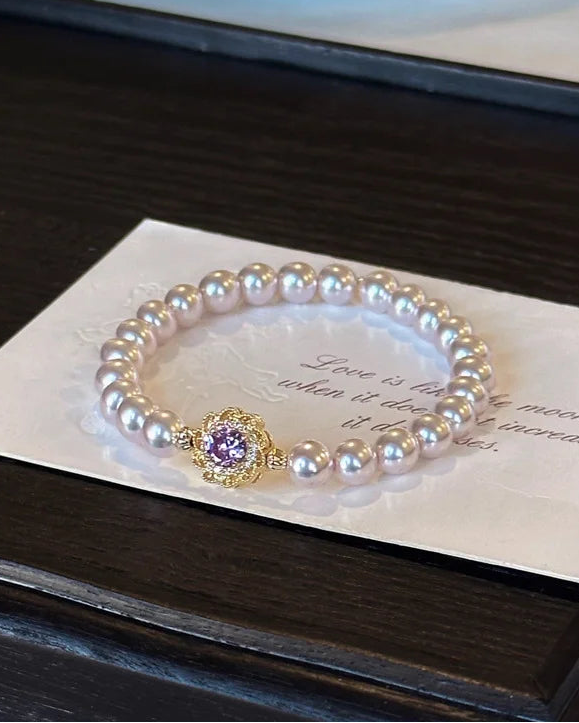 Lia's Lavendel-Blüte Armband aus zartvioletten Kunstperlen mit einem blumenförmigen goldenen Anhänger und violettem Zirkonia