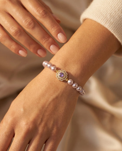 Lia's Lavendel-Blüte Armband aus zartvioletten Kunstperlen mit einem blumenförmigen goldenen Anhänger und violettem Zirkonia