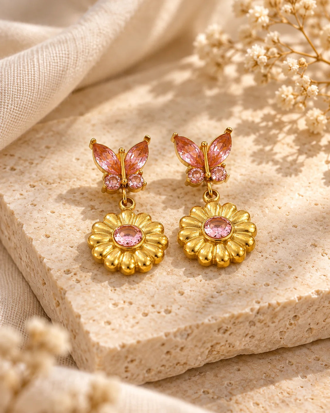 Goldene Schmetterling Ohrringe mit rosa Zirkonia auf natürlichem Hintergrund