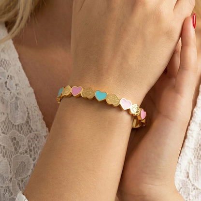Zwei Titanstahl-Armreifen "Lottie" in Gold und Silber mit bunten Emaille-Herzen (Rosa/Grün)