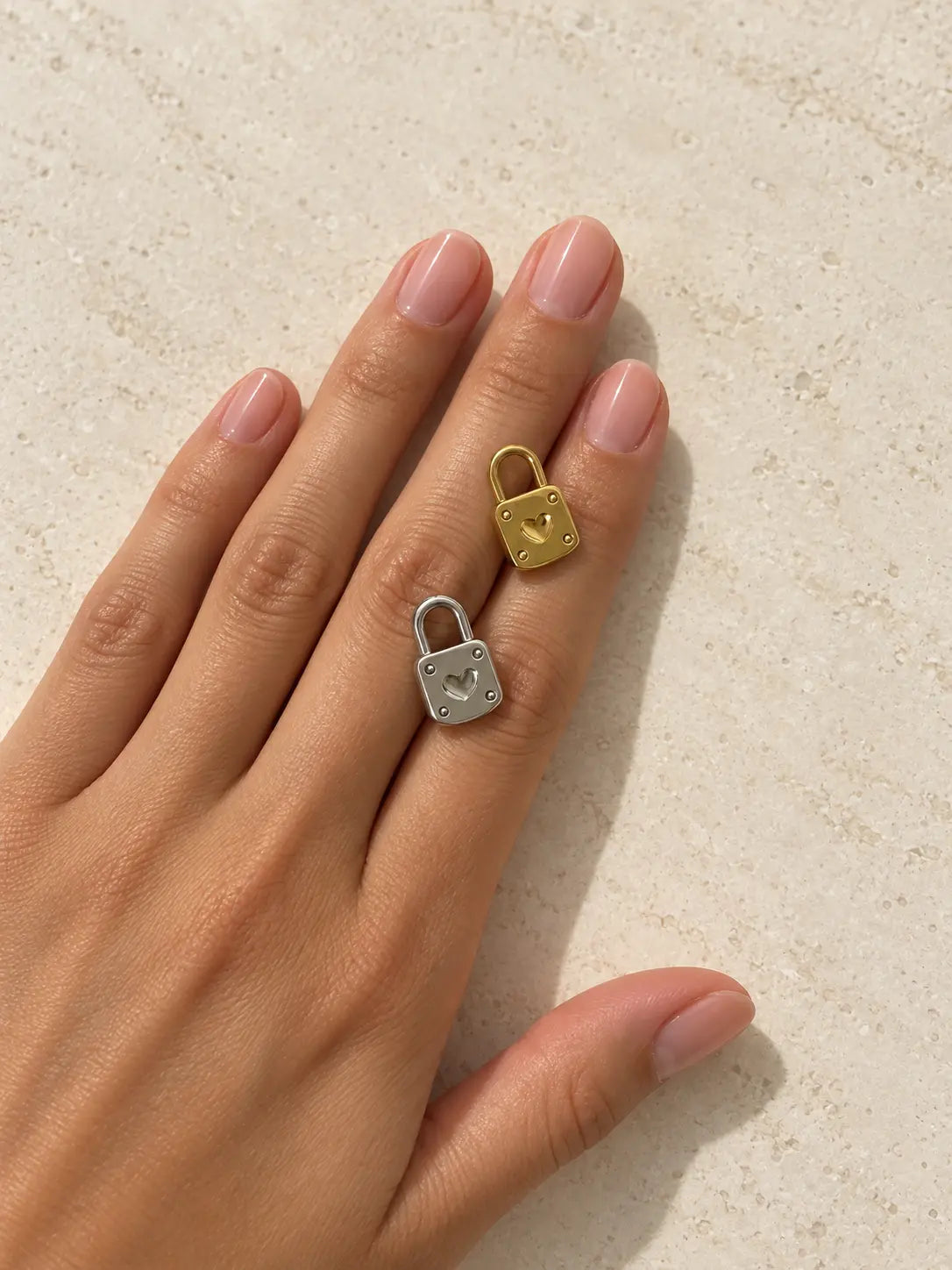 Goldener und silberfarbener Luna Schloss Charm mit Herzmotiv auf einer Hand vor hellem Steinhintergrund