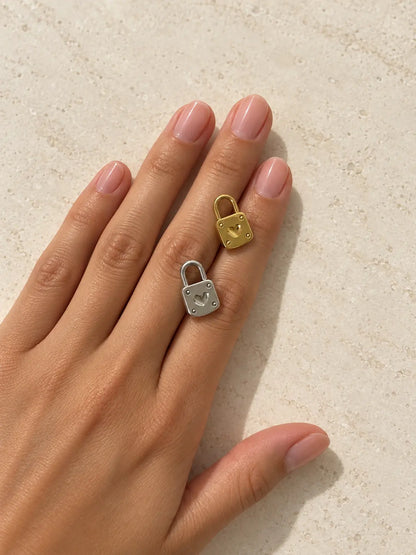 Goldener und silberfarbener Luna Schloss Charm mit Herzmotiv auf einer Hand vor hellem Steinhintergrund