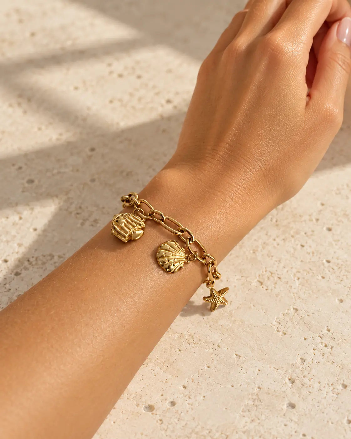 Maris goldenes Charm Armband am Handgelenk getragen