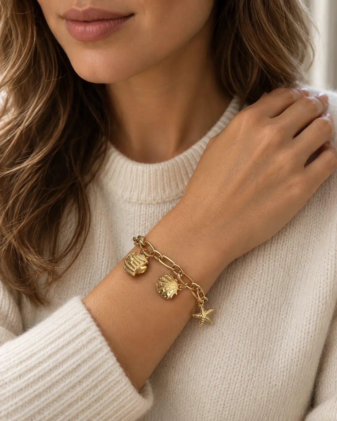 Maris goldenes Charm Armband am Handgelenk getragen