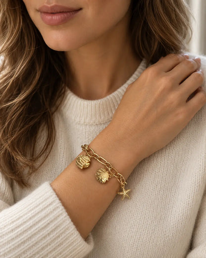Maris goldenes Charm Armband am Handgelenk getragen