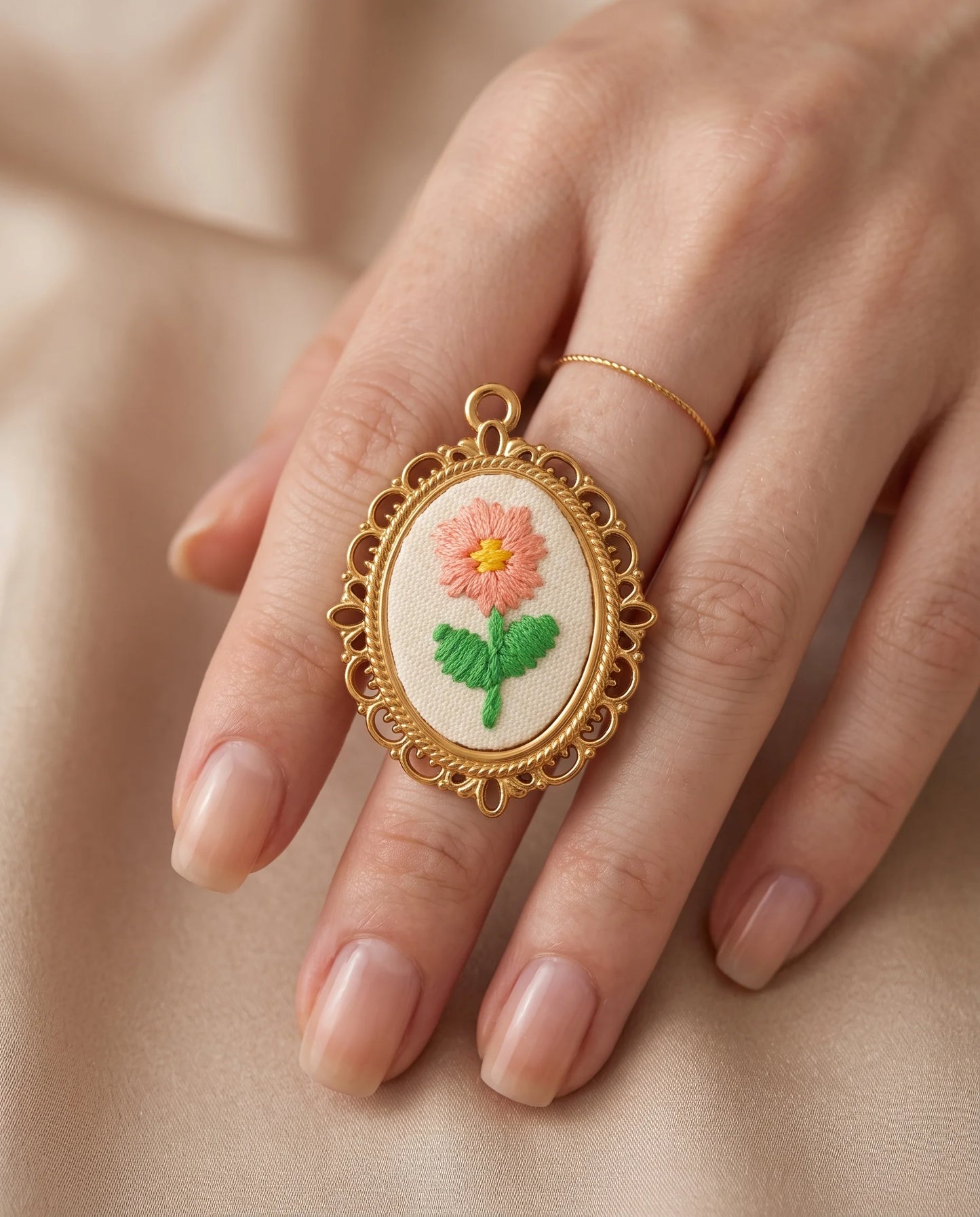 Matilda Stickerei Charm aus vergoldetem Titanstahl im Detail