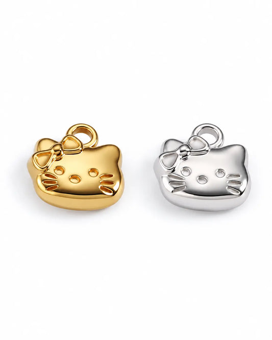 Mimi Katzen Charms in Gold und Silber mit Schleife und Schnurrhaardetails auf weißem Hintergrund